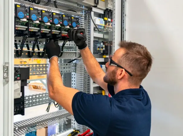 Electricidad para comercios lista y en regla Técnico con gafas de protección trabajando en un cuadro eléctrico de gran tamaño en Málaga