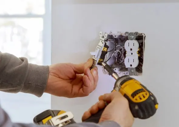 Electricista fijando un mecanismo en su caja de empotrar con atornillador en Málaga